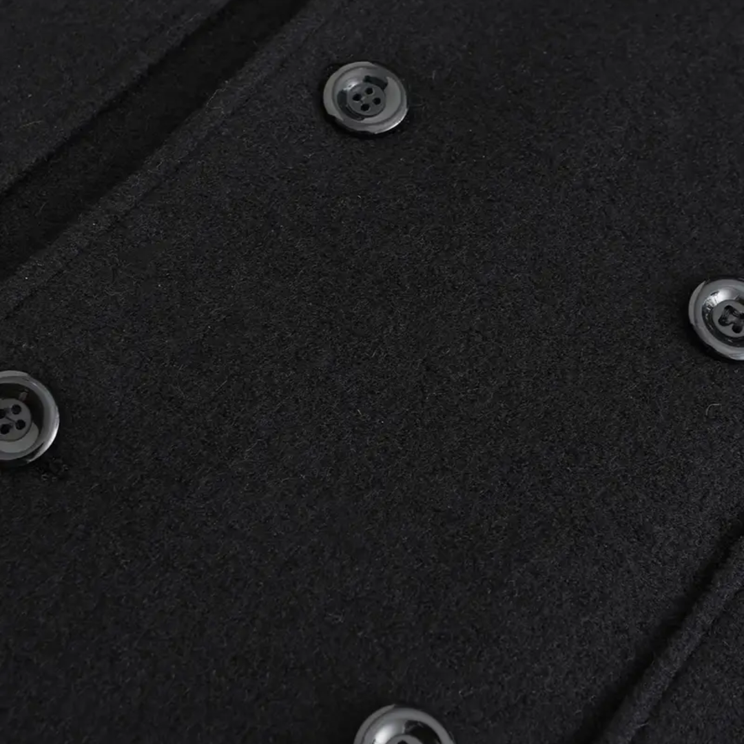 Detail of men's black double-breasted overcoat. Tailored lapels & quality fabric of this elegant winter long coat for men.