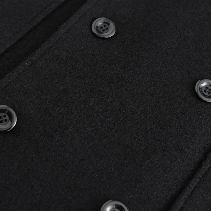 Detail of men's black double-breasted overcoat. Tailored lapels & quality fabric of this elegant winter long coat for men.