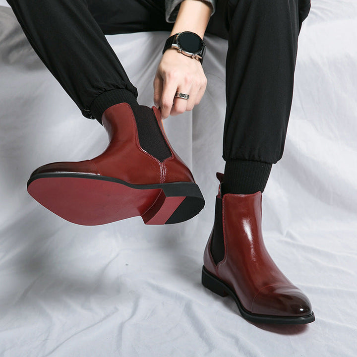 A pair of men's elegant Chelsea boots, black, featuring a sleek design and a stylish red bottom.