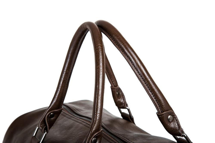 Men's leather carry-on bag in black, placed casually on a bench, highlighting its versatile travel style