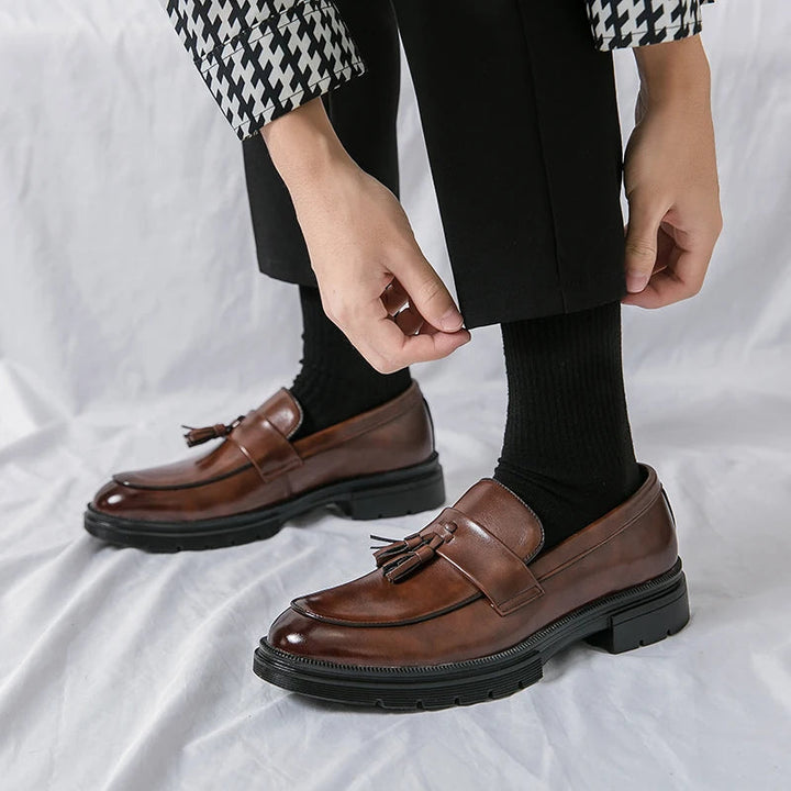 Back detail of men's comfortable black leather tassel loafers. Elegant slip-on footwear for a classic look.