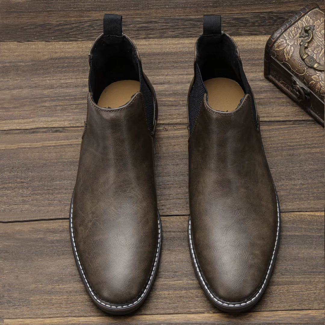 Close-up of men's brown leather Chelsea boots, showcasing texture, classic & durable design.