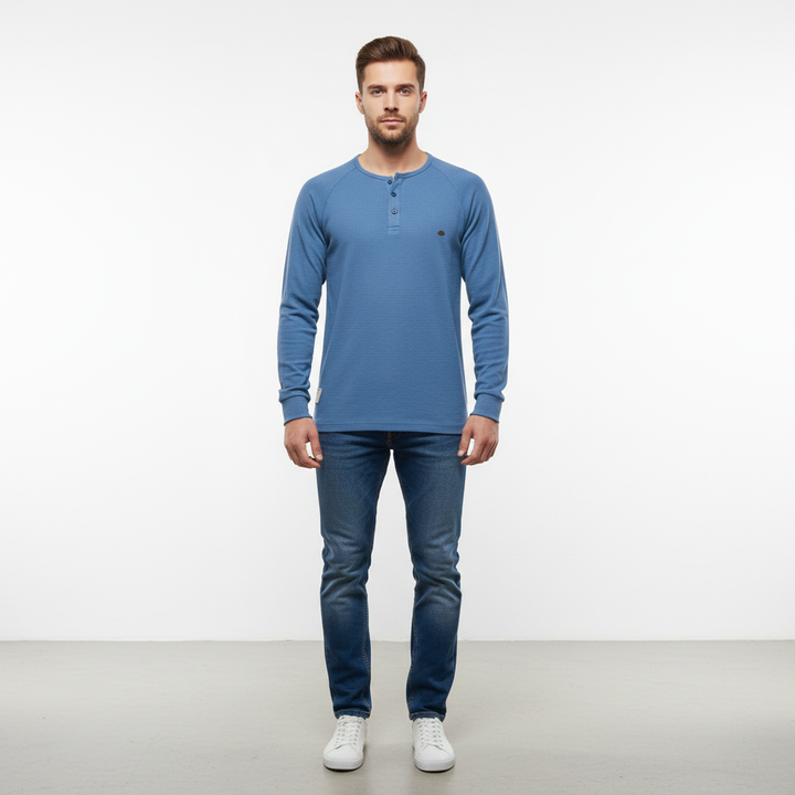 Man wearing a casual men's cotton-poly long sleeve shirt in a natural outdoor setting, autumn fashion.