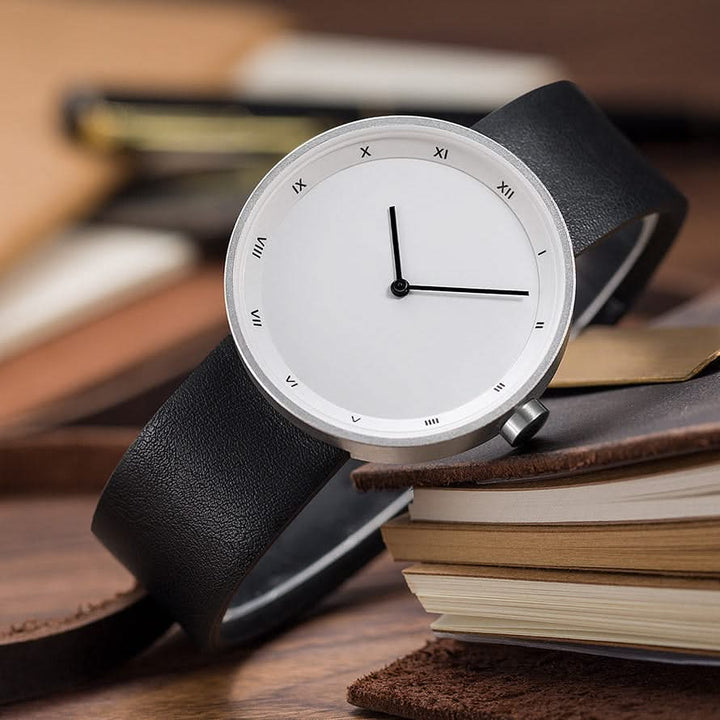 Minimalist men's accessory: classic Roman numeral watch with a sophisticated brown leather strap for him.