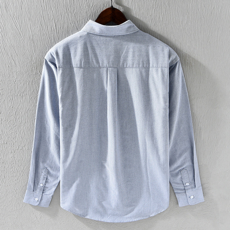 Man wearing a classic white Oxford shirt with elegant ribbon trim. Button-down, perfect for formal or casual outfits.