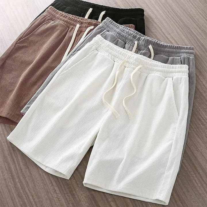 Relaxed fit men's waffle knit lounge shorts featuring a drawstring waist & convenient pockets. Ideal summer attire.