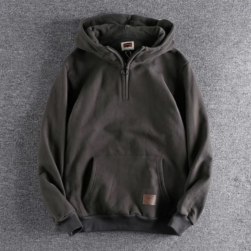Close-up of a men's quarter-zip hoodie in relaxed fit, highlighting cozy fabric & versatile design.