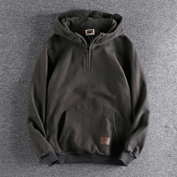 Close-up of a men's quarter-zip hoodie in relaxed fit, highlighting cozy fabric & versatile design.