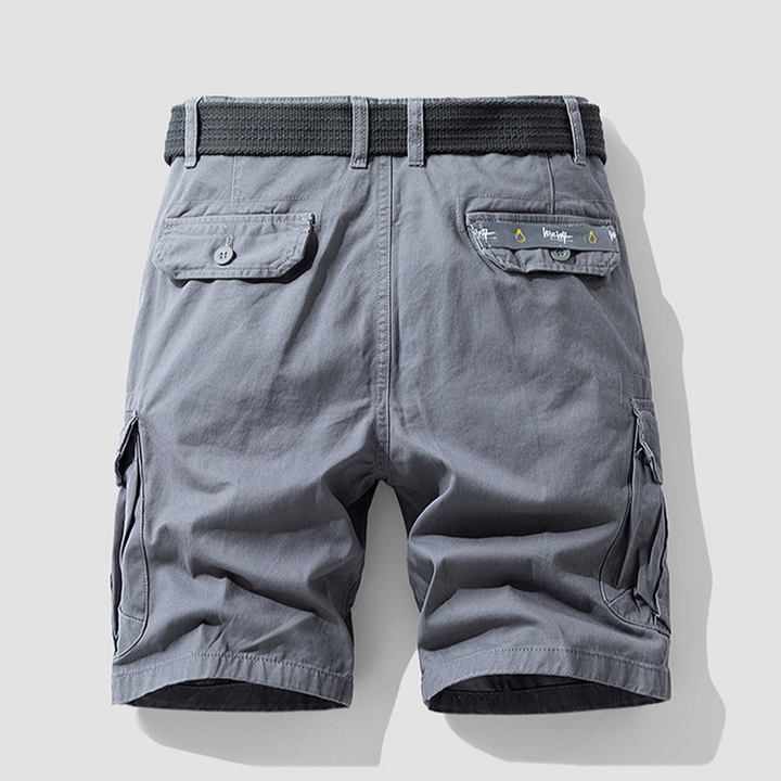 Man hiking in green adventure cargo shorts, demonstrating durability & freedom of movement in outdoor wear.