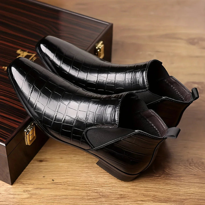 Side view of men's black crocodile embossed Chelsea boots, highlighting elastic goring & elegant finish.