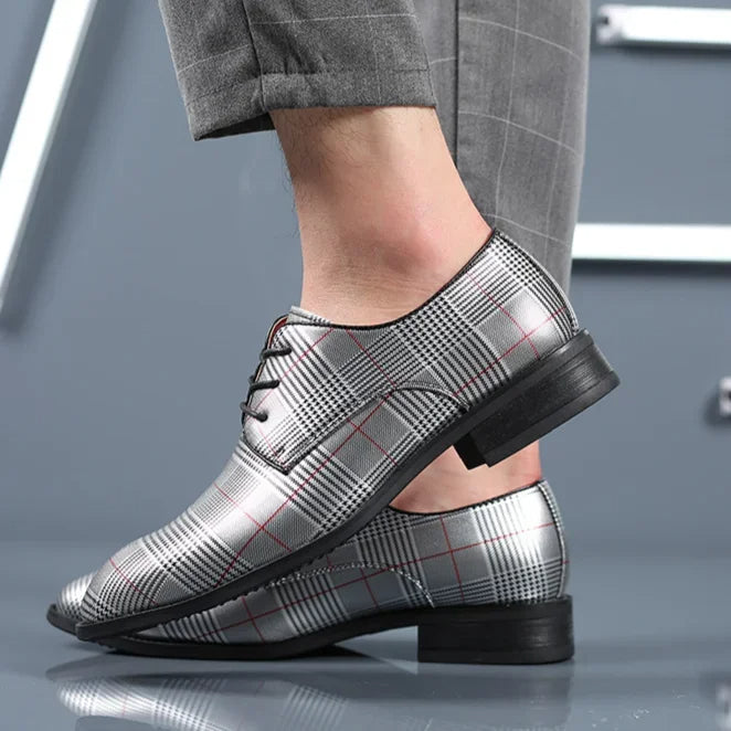 Close-up of men's oxford dress shoes, showcasing black leather with stylish plaid contrast detail.