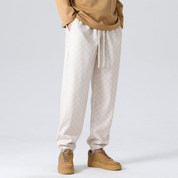 Side view of men's checkerboard sweatpants, black & cream, featuring comfortable wide leg & pockets.