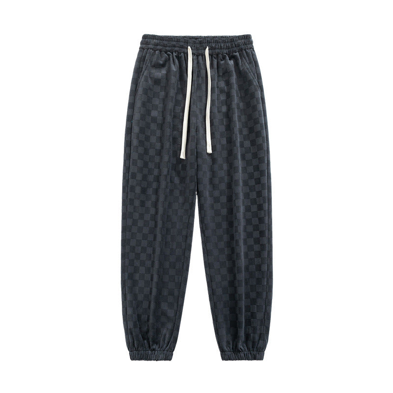 Dynamic shot of men's checkerboard wide-leg sweatpants, gray & black, for an edgy streetwear look.