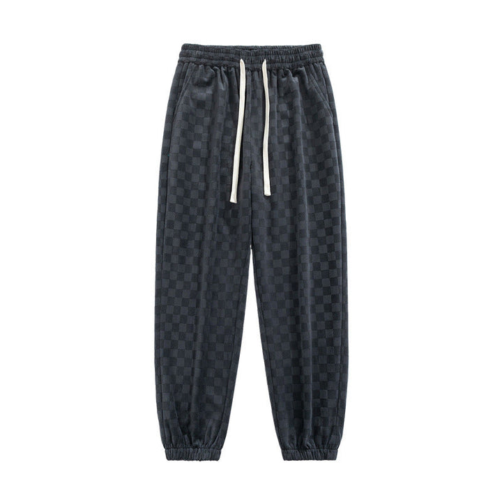 Dynamic shot of men's checkerboard wide-leg sweatpants, gray & black, for an edgy streetwear look.