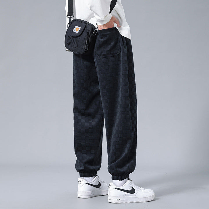 Relaxed fit men's checkerboard activewear sweatpants in black & cream, combining comfort & style.