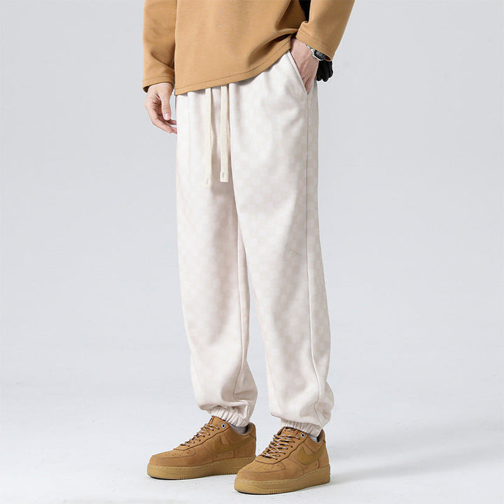 Man wearing stylish gray checkerboard wide-leg sweatpants, showcasing full relaxed fit and design.