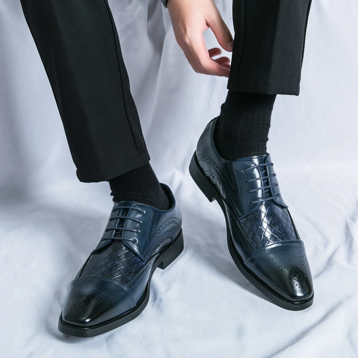 Close-up of sophisticated men's brogue dress shoes showing intricate perforations and lace-up detail.
