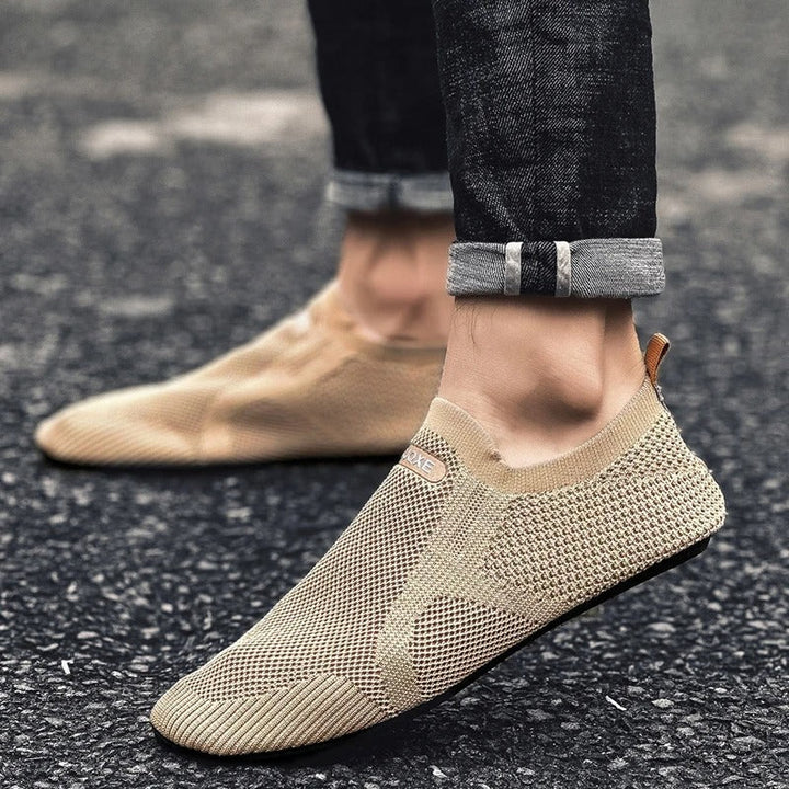 Man's foot in black knit slip-on shoes. Lightweight, flexible, laceless for ultimate comfort.
