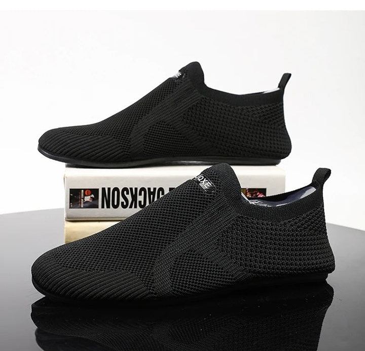 Top view of black men's knit slip-on shoes. Barefoot comfort, breathable fabric, laceless.