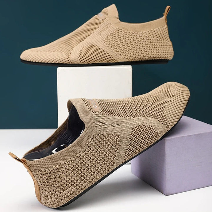 Pair of black men's knit slip-on walking shoes. Breathable, laceless design for easy wear.