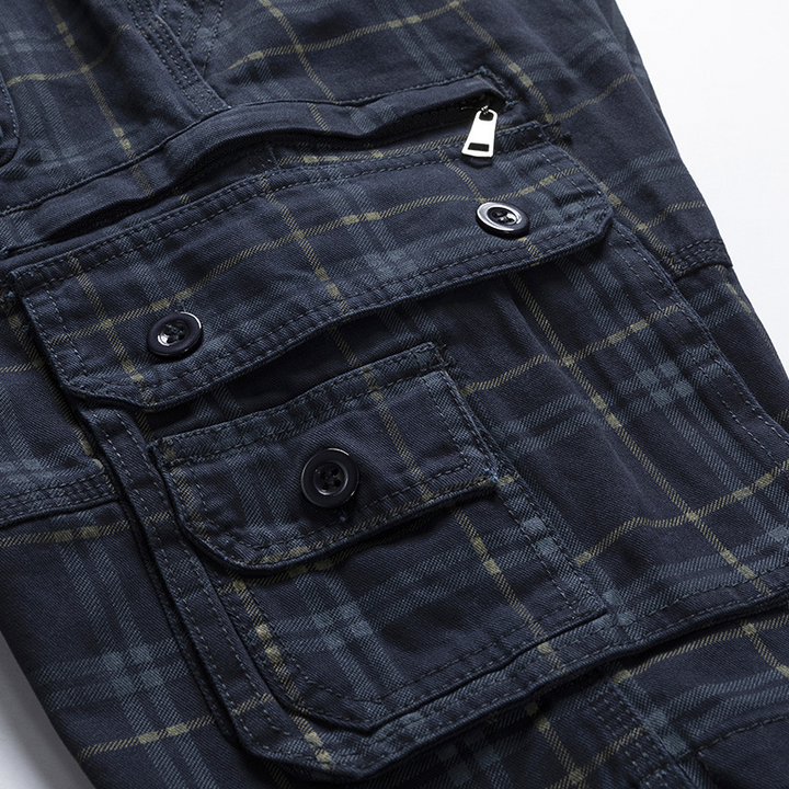 Man wearing men's lightweight adventure cargo shorts in check pattern, walking outdoors, side view.