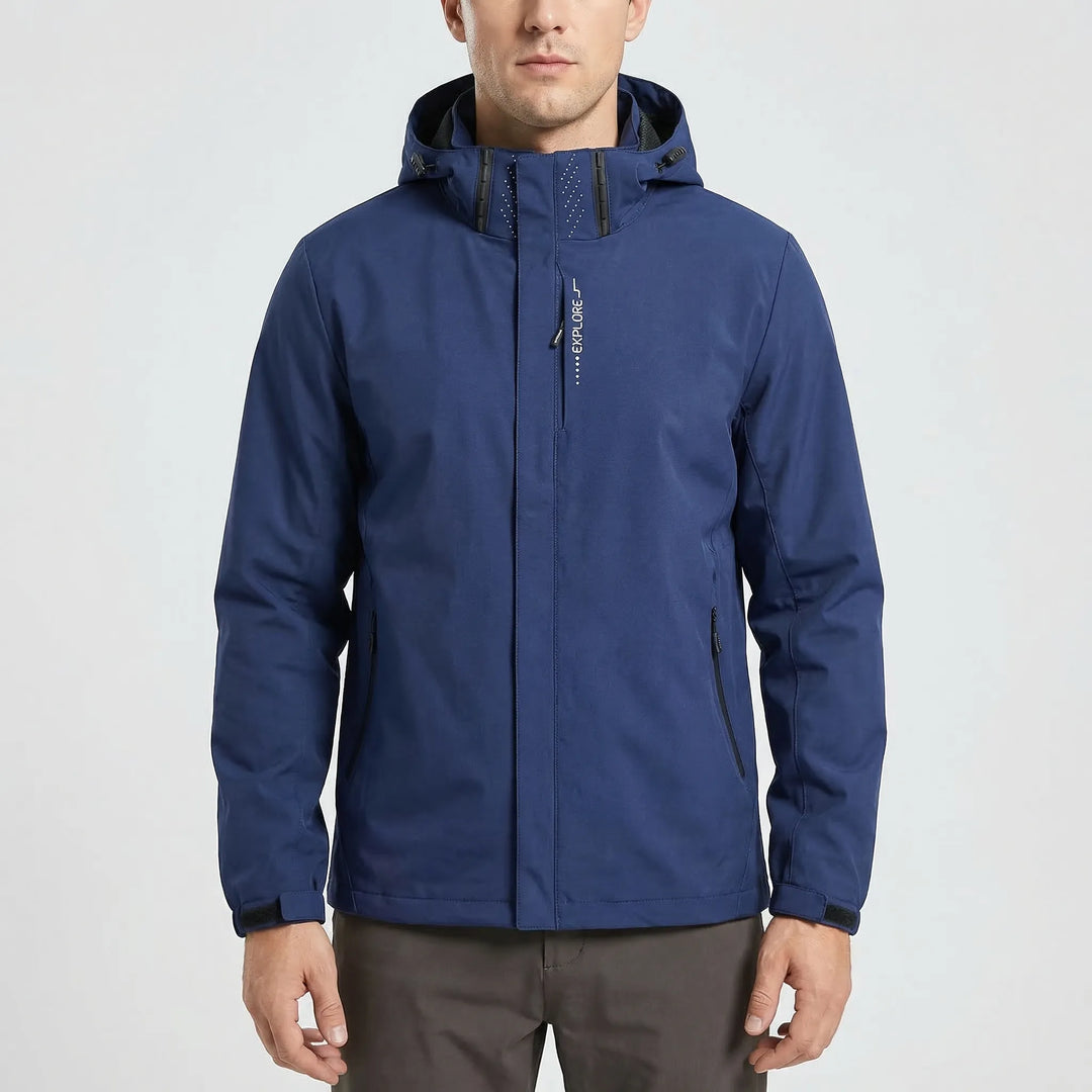 Man hiking in a forest, wearing a blue lightweight hooded windbreaker jacket, enjoying the outdoors.