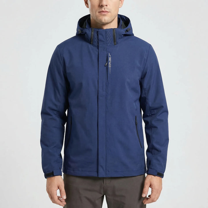 Man hiking in a forest, wearing a blue lightweight hooded windbreaker jacket, enjoying the outdoors.