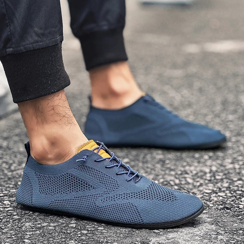 Man wearing black mesh knit slip-on sneakers, walking comfortably outdoors.