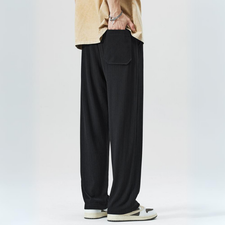 Close-up: Milano pleated men's trousers, highlighting fabric texture, pleats, and comfortable elastic waistband.