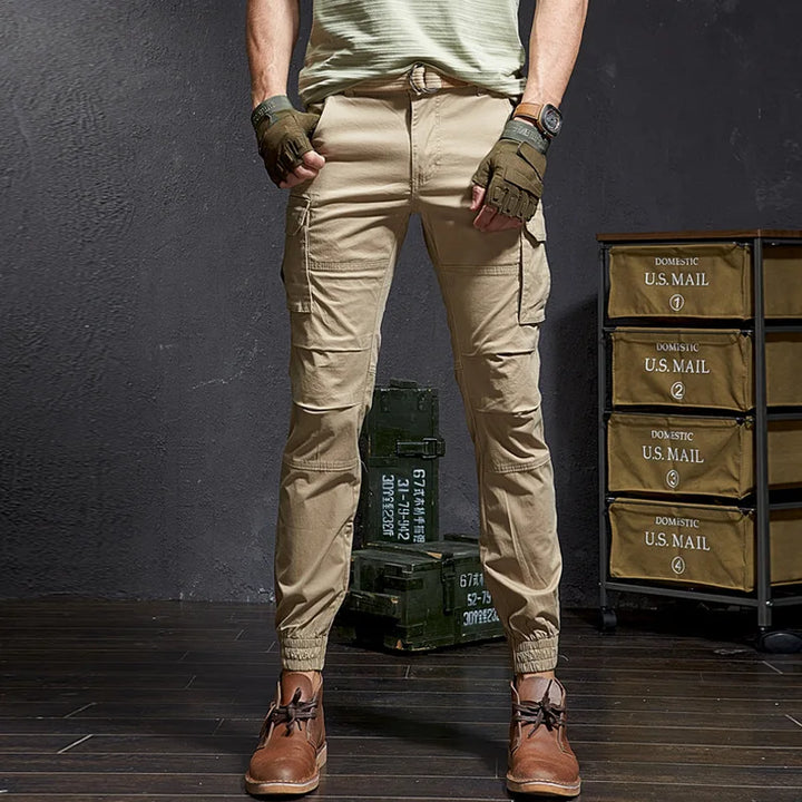 Rugged men's Outland tapered cargo pants with multiple tactical utility pockets, ideal for streetwear & outdoor use.