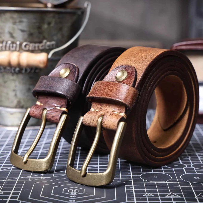 Angled view of a men's premium brown cowhide leather belt, highlighting its polished buckle and smooth texture.