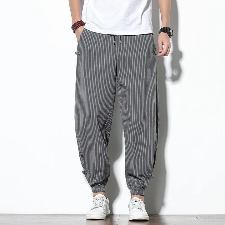 Relaxed fit men's pinstripe pants, featuring a drawstring waist for adjustable, all-day comfort.