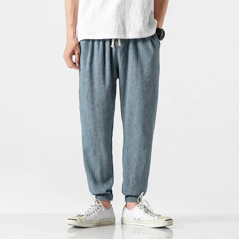 Close-up of men's tapered joggers showing elastic waist & drawstring, emphasizing relaxed fit comfort.