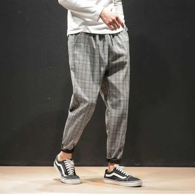 Close-up of the woven plaid fabric on stylish men's stretch trousers, highlighting quality.