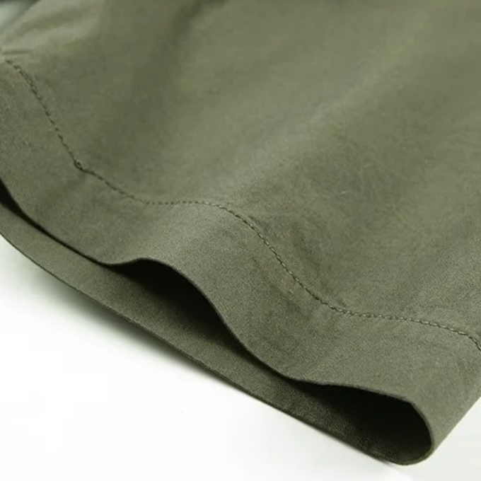 Close-up of durable stitching on a men's rugged cotton short sleeve shirt, highlighting quality & utility.
