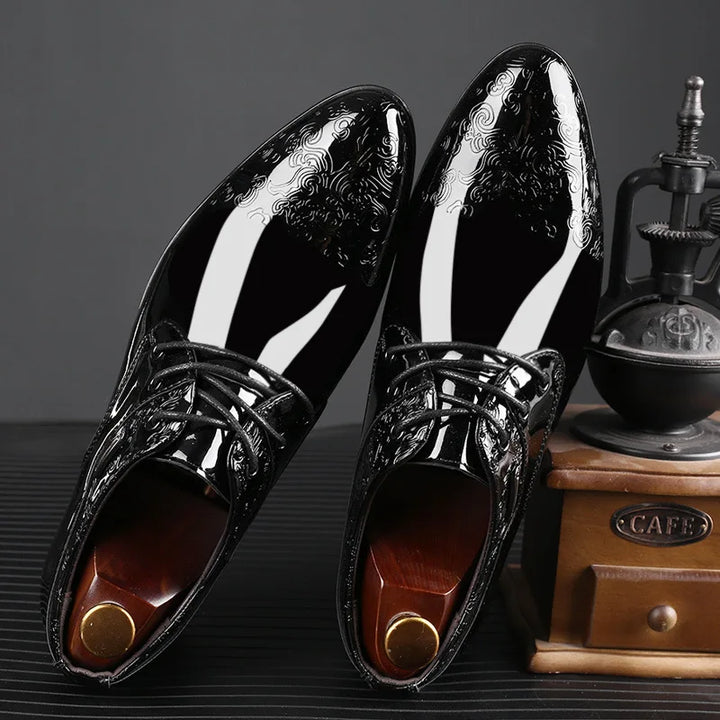 Close-up of a men's glossy black lace-up dress shoe, featuring classic Oxford styling.