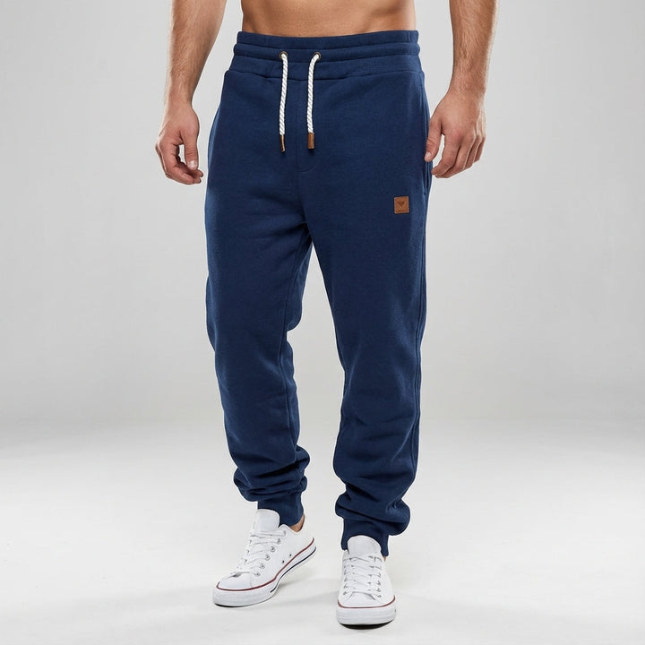 Man wearing slim fit performance joggers in navy, demonstrating athletic build & comfortable fit