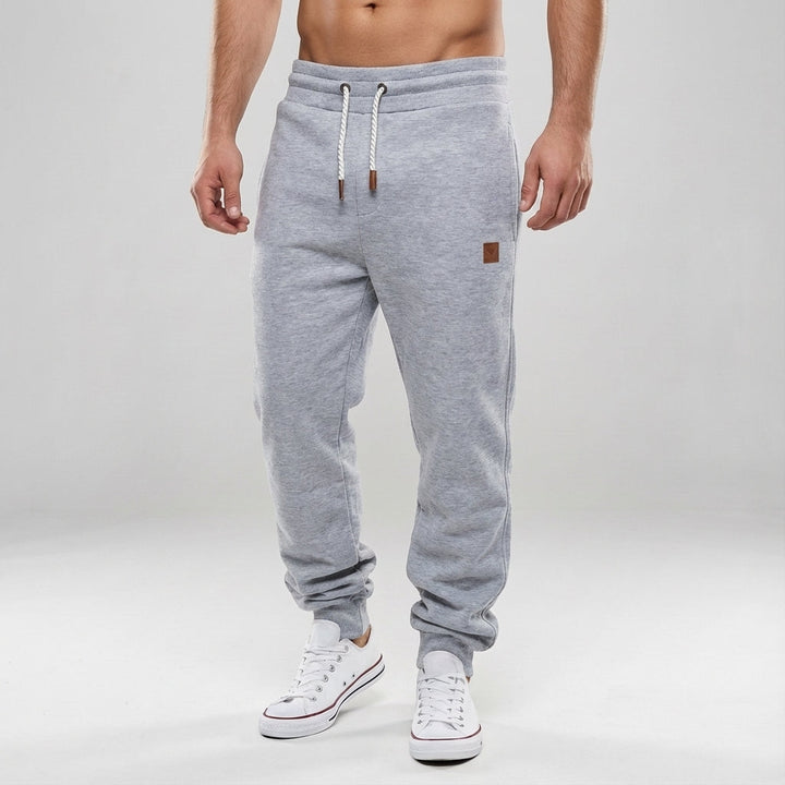 Folded men's slim fit joggers in various colors, showcasing sportswear and casual trousers