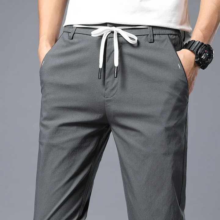 Close-up of modern men's slim fit pants, highlighting drawstring waist & wrinkle-resistant fabric.