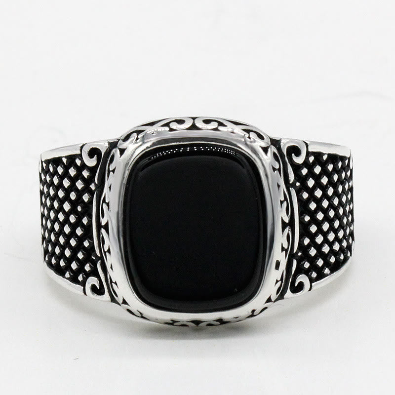 Close-up of a polished black onyx gemstone set in a sterling silver men's ring band.