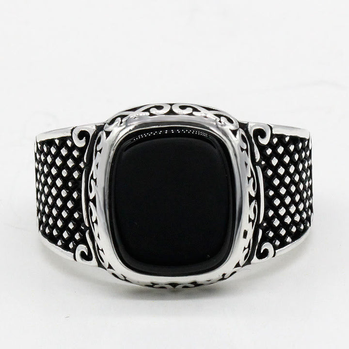 Close-up of a polished black onyx gemstone set in a sterling silver men's ring band.