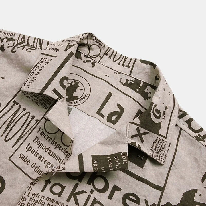 Folded men's stylish newspaper print short-sleeve button-up shirt, ready for a unique casual streetwear look.