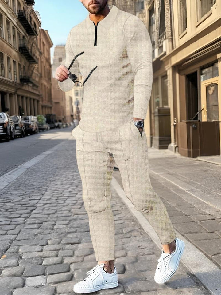 Model showcasing a men's comfortable zip-neck lounge set. Two-piece cotton blend for stylish, casual men's fashion.