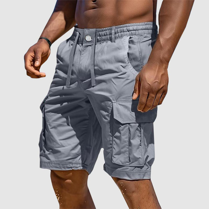 Man in functional men's summer adventure cargo shorts. Cotton-mix with utility pockets, perfect for outdoor travel.