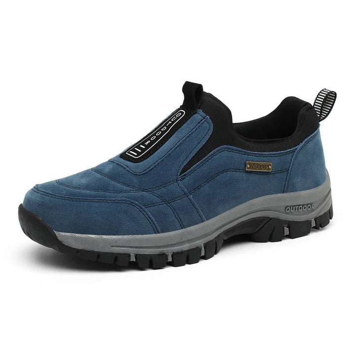 Man wearing supportive orthopedic hiking shoes on a mountain trail, ideal for outdoor comfort.
