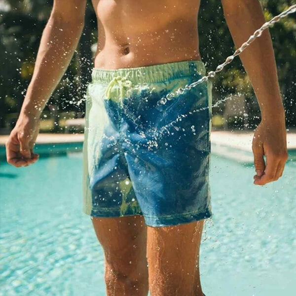 Quick-dry color-changing boardshorts for men, showing activated thermal effect on the beach