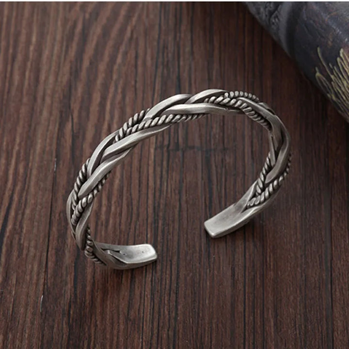 Close-up: Men's sterling silver cuff bracelet, showcasing its unique twisted design & polished finish. Adjustable jewelry.