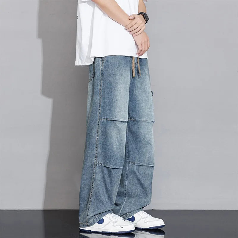 Close-up of men's wide-leg washed jeans showing drawstring waist and relaxed fit. Stylish casual pants.