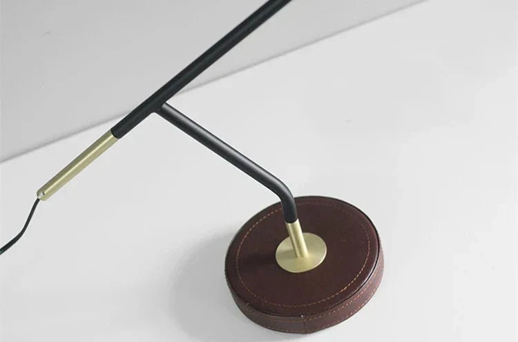 Deskora adjustable desk lamp with a sophisticated leather base and gold accents, well-suited for any modern office.