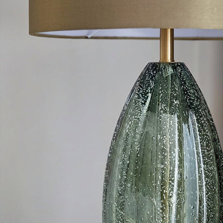Decorative table lamp featuring a sleek green glass base and a complementary fabric shade for ambient light.